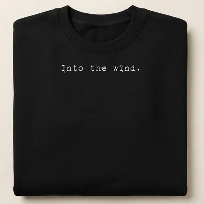 Minimalist white t-shirt with the text 'Into the wind.' — printed on a unisex sweatshirt