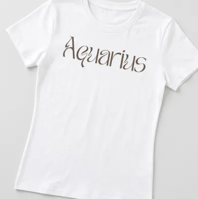 Elegant script reading Aquarius in brown on a celestial-themed — printed on a women's shirt