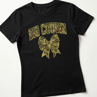 Cartoon style camouflage bow with bold 'BIG COUSIN' text in greens and browns — printed on a women's shirt