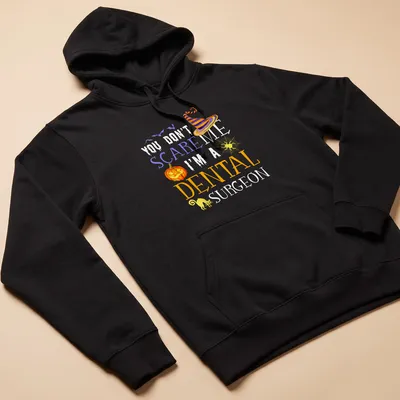 Whimsical Halloween shirt featuring a dental surgeon with playful text. — printed on a unisex hoodie