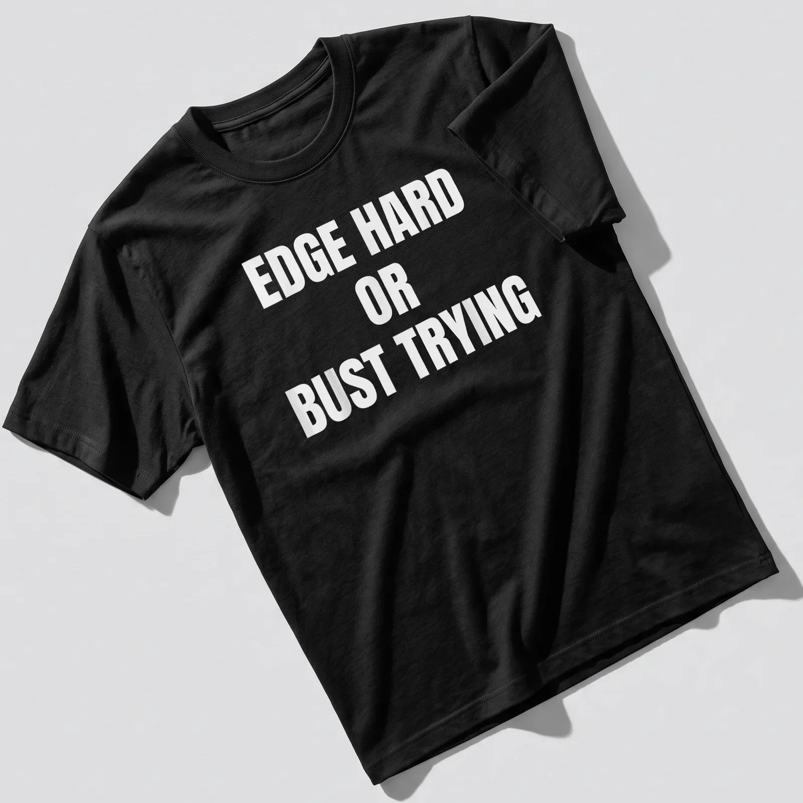 Bold typography t-shirt with the quote 'EDGE HARD OR BUST TRYING' on a white background — printed on a unisex t-shirt