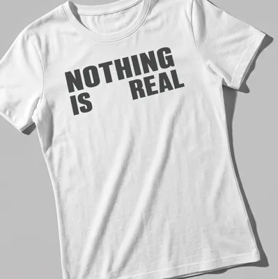 Minimalist typography t-shirt with black and white design stating 'NOTHING IS REAL' — printed on a women's shirt