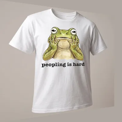Cartoon frog with text 'peopling is hard' in a funny introvert — printed on a unisex t-shirt (angled view)