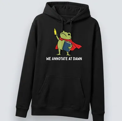 Cartoon frog reading a book, featuring vibrant colors and playful text. — printed on a unisex hoodie