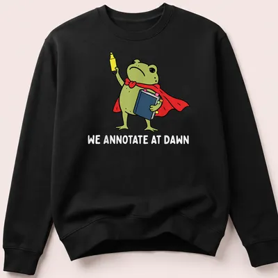 Cartoon frog reading a book, featuring vibrant colors and playful text. — printed on a unisex sweatshirt