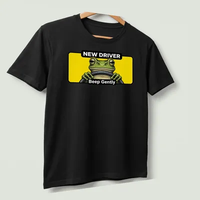 Cartoon green frog with text 'NEW DRIVER Beep Gently' in yellow and black — printed on a unisex t-shirt (angled view)