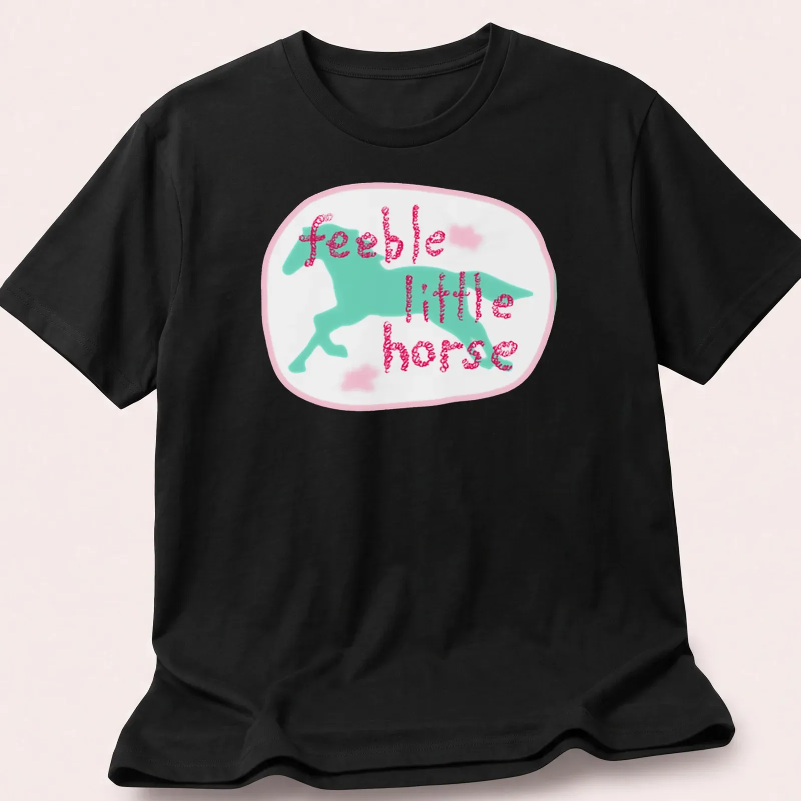 Cartoon design of a playful horse with the text feeble little horse in pink and blue. — printed on a unisex t-shirt