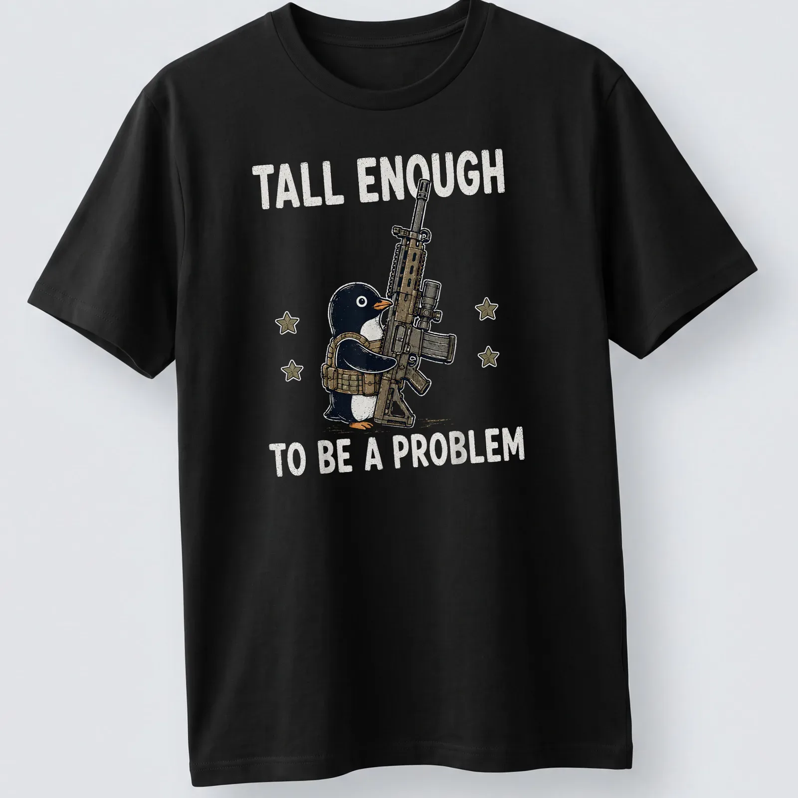 Cartoon penguin with a gun and the text 'Tall Enough To Be A Problem' in black and white — printed on a unisex t-shirt